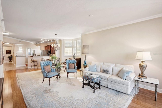 living room with ornamental molding, light hardwood / wood-style flooring, and a notable chandelier