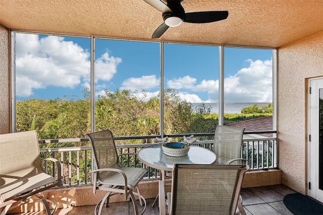 sunroom / solarium with a wealth of natural light, a water view, and ceiling fan