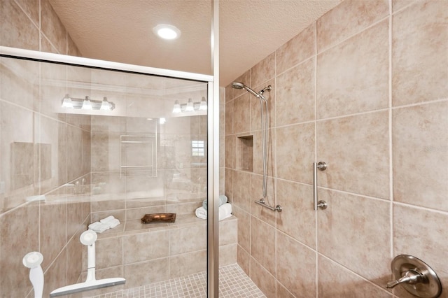 bathroom featuring a shower with shower door and a textured ceiling