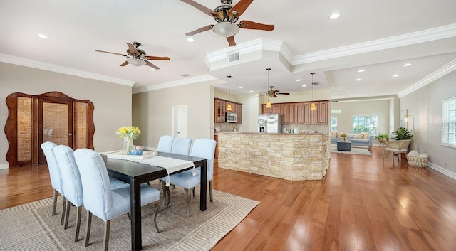 dining space featuring ornamental molding and light hardwood / wood-style flooring