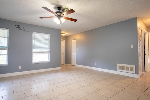 empty room with ceiling fan, plenty of natural light, and a textured ceiling