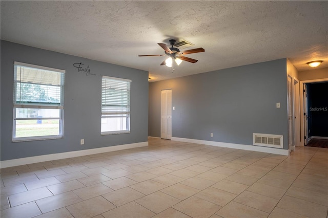 tiled spare room with a textured ceiling and ceiling fan