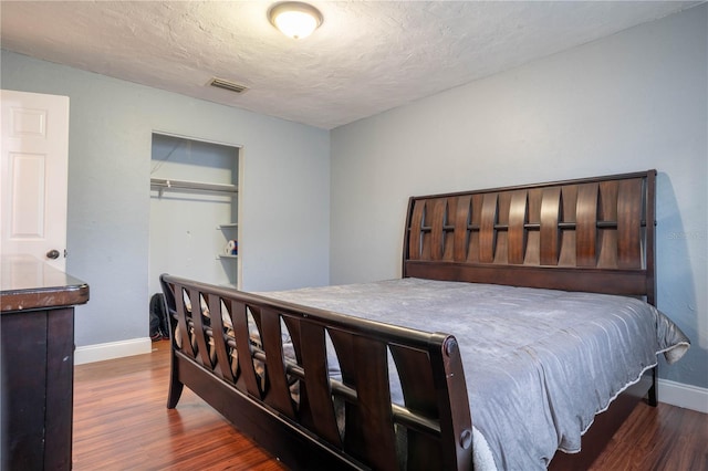 bedroom featuring dark wood-type flooring, a textured ceiling, and a closet