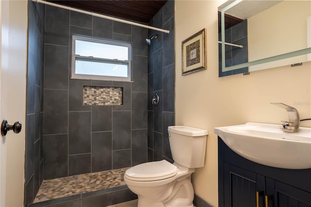 bathroom with toilet, vanity, and a tile shower