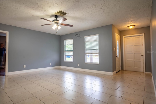 spare room featuring a textured ceiling, light tile patterned floors, and ceiling fan