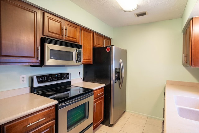 kitchen featuring sink, a textured ceiling, light tile patterned floors, and stainless steel appliances