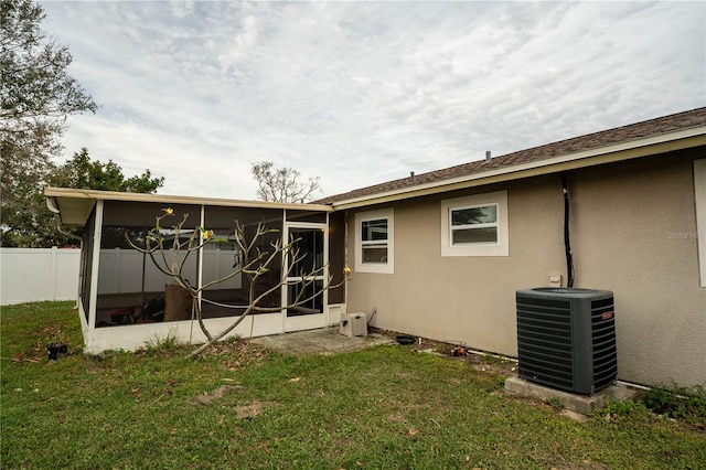 rear view of house featuring central air condition unit, a sunroom, and a yard