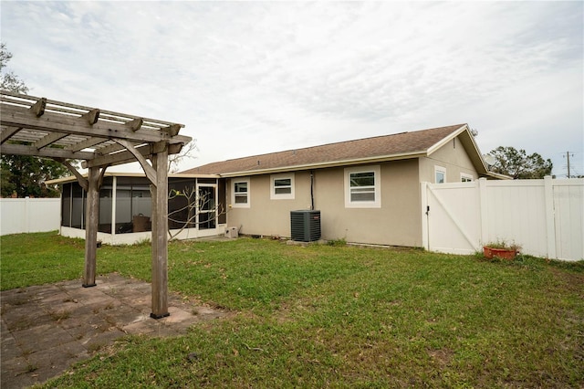 back of property featuring central air condition unit, a lawn, a sunroom, and a pergola