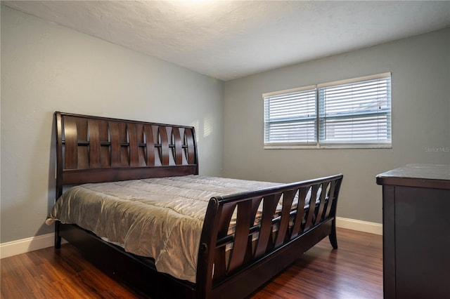 bedroom with a textured ceiling and dark hardwood / wood-style floors