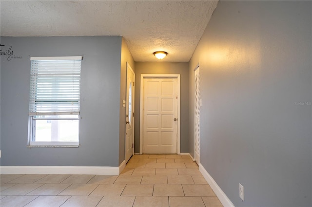 doorway to outside featuring a textured ceiling and light tile patterned flooring