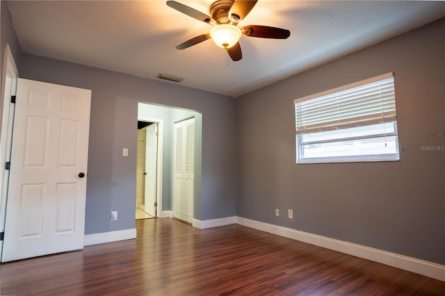 unfurnished bedroom featuring dark wood-type flooring, ceiling fan, and a closet