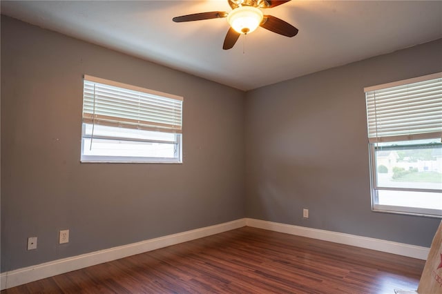 empty room featuring ceiling fan, a wealth of natural light, and dark hardwood / wood-style floors