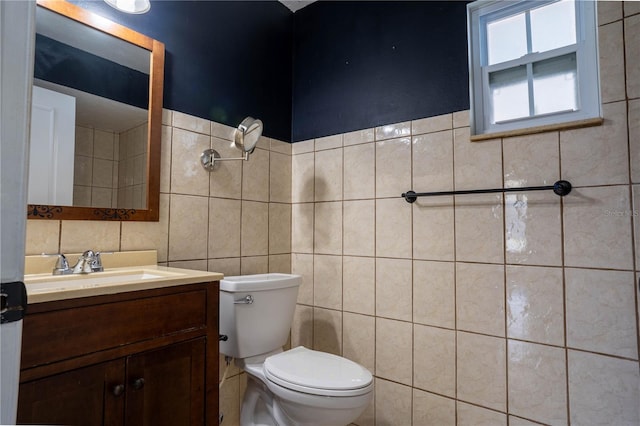 bathroom with toilet, vanity, and tile walls