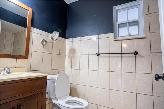 bathroom with toilet, vanity, and tile walls