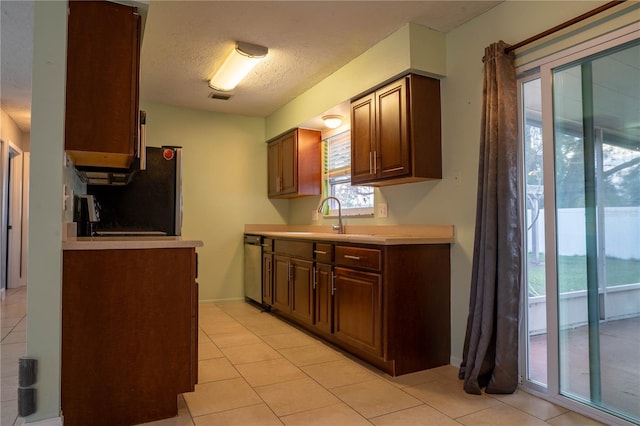 kitchen with a textured ceiling, a water view, sink, and light tile patterned floors