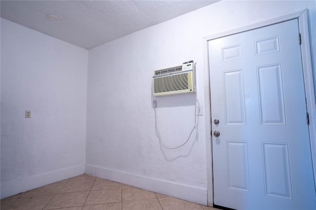 unfurnished room featuring a textured ceiling, light tile patterned floors, and a wall mounted air conditioner