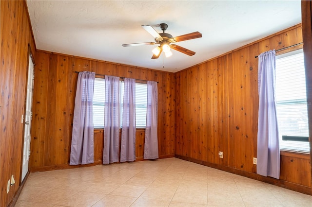 spare room with wood walls and ceiling fan