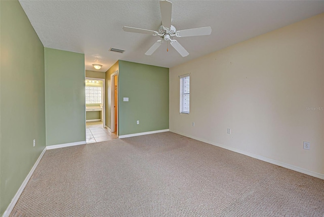 spare room featuring ceiling fan, light colored carpet, and a textured ceiling