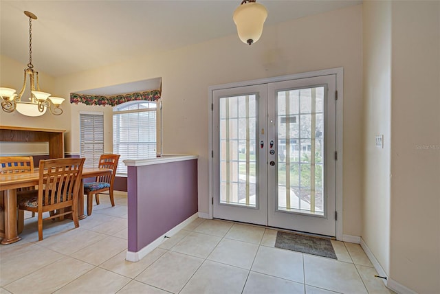 tiled foyer with french doors, plenty of natural light, and an inviting chandelier