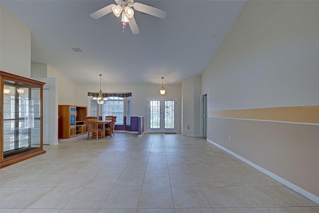 spare room featuring light tile patterned flooring, ceiling fan with notable chandelier, vaulted ceiling, and french doors