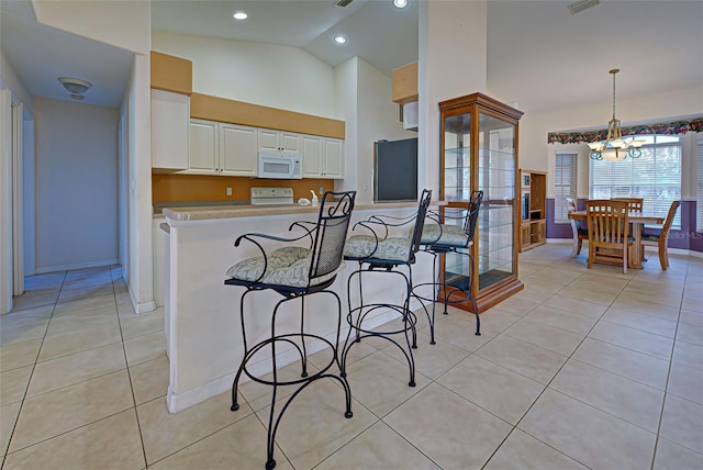 kitchen featuring white appliances, light tile patterned floors, pendant lighting, white cabinets, and a chandelier