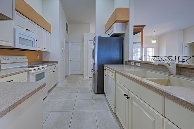 kitchen featuring light tile patterned floors, pendant lighting, sink, white cabinets, and white appliances