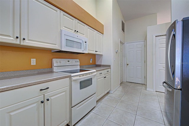 kitchen featuring white cabinetry, light tile patterned floors, and white appliances