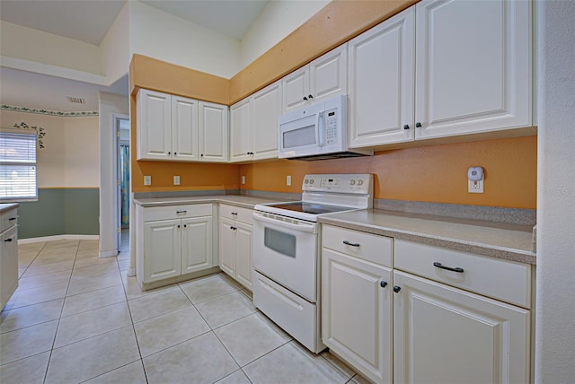 kitchen with white appliances, white cabinetry, and light tile patterned flooring