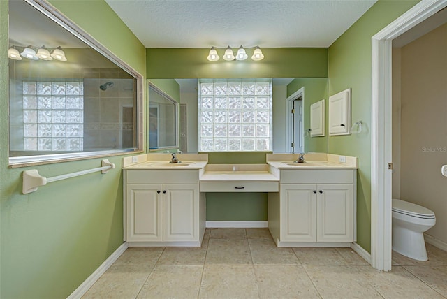 bathroom featuring toilet, vanity, a textured ceiling, and a healthy amount of sunlight