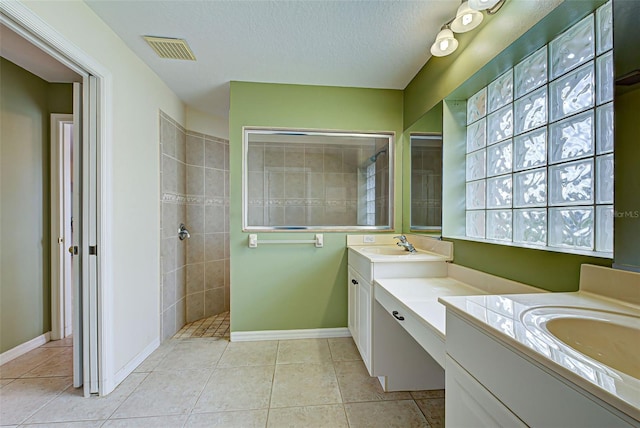 bathroom with vanity, a textured ceiling, tile patterned flooring, and a tile shower