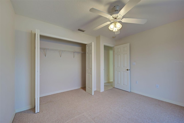 unfurnished bedroom featuring light colored carpet, ceiling fan, and a closet