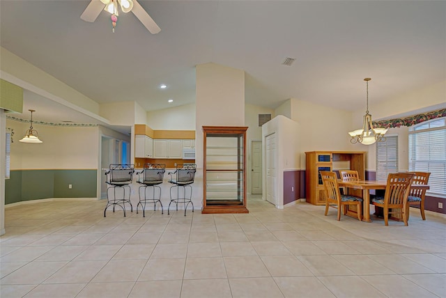 kitchen featuring ceiling fan with notable chandelier, pendant lighting, a kitchen breakfast bar, light tile patterned flooring, and white cabinetry