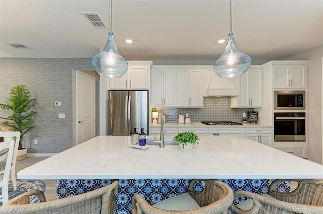 kitchen with white cabinets, custom range hood, stainless steel appliances, and pendant lighting