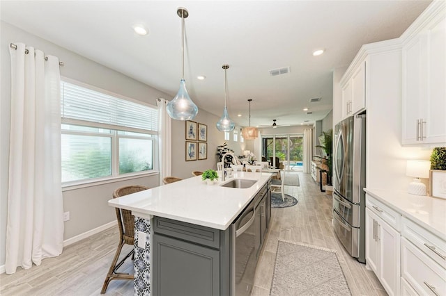 kitchen featuring a kitchen bar, an island with sink, light hardwood / wood-style floors, stainless steel appliances, and white cabinets