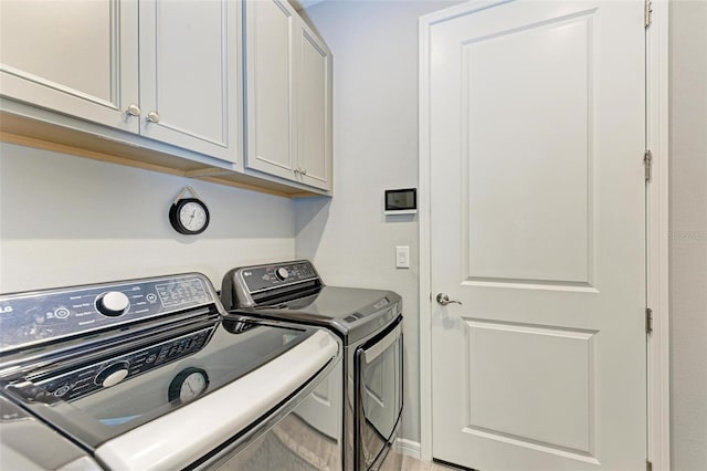 washroom featuring cabinets and washing machine and clothes dryer