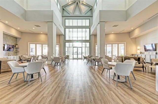 dining area featuring light hardwood / wood-style flooring, a towering ceiling, and a wealth of natural light