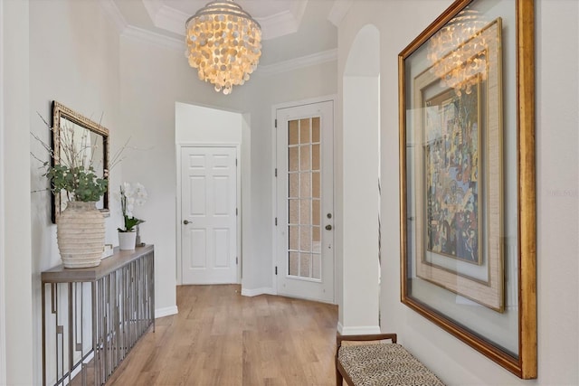 interior space featuring light wood-type flooring, a tray ceiling, a notable chandelier, and ornamental molding