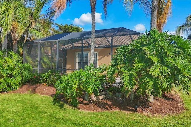 view of property exterior with stucco siding, a lanai, a tiled roof, and a lawn