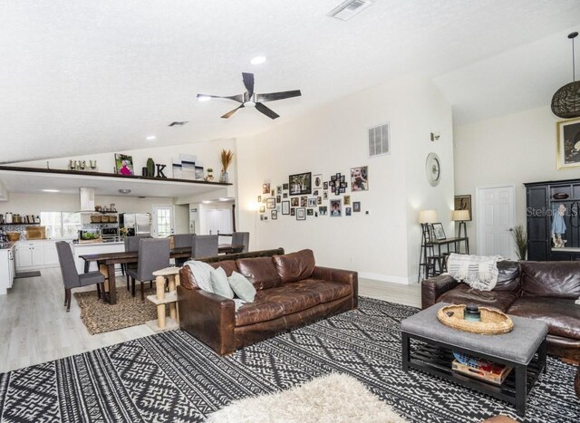 living room with vaulted ceiling, light wood-type flooring, and ceiling fan