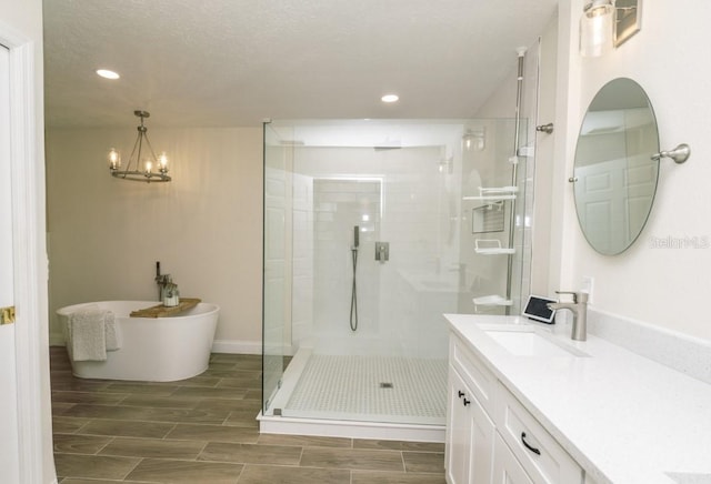 bathroom featuring vanity, a notable chandelier, a textured ceiling, and plus walk in shower