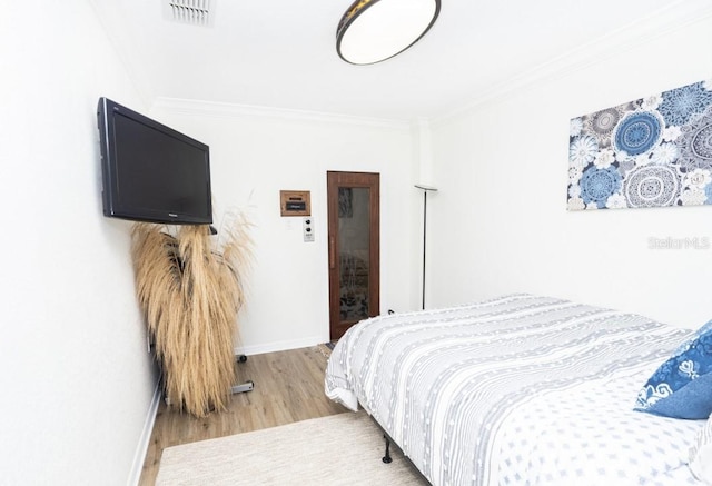 bedroom with hardwood / wood-style floors and crown molding