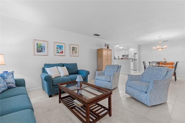 living area with light tile patterned floors, a textured ceiling, a notable chandelier, visible vents, and baseboards