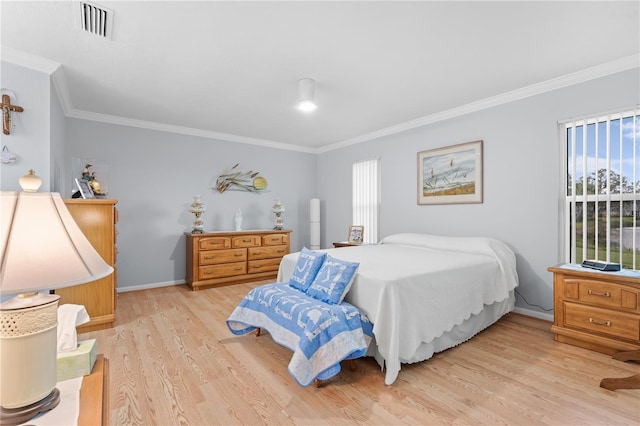 bedroom with ornamental molding, light wood finished floors, visible vents, and baseboards