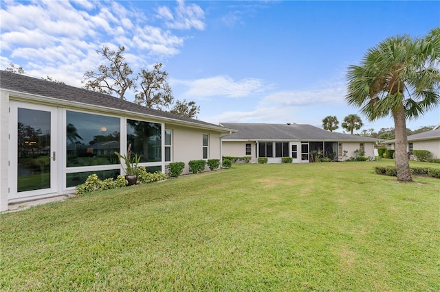 rear view of property with a yard and stucco siding