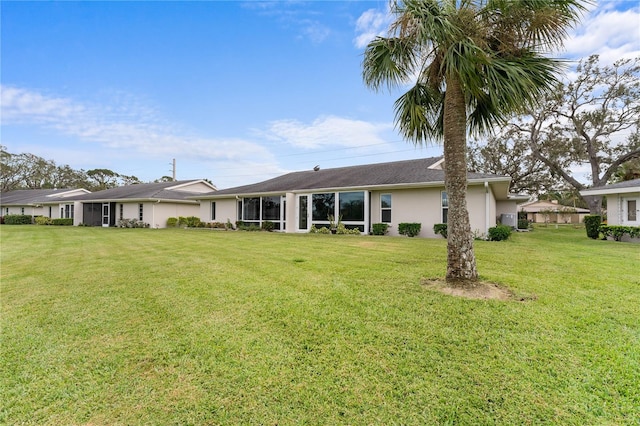 rear view of house with a lawn and stucco siding