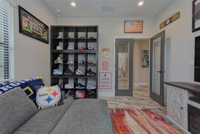 living area with french doors and light hardwood / wood-style flooring