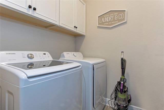 washroom with washer and dryer and cabinets