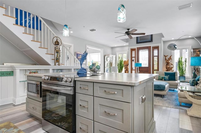 kitchen featuring appliances with stainless steel finishes, pendant lighting, light wood-type flooring, and a wealth of natural light