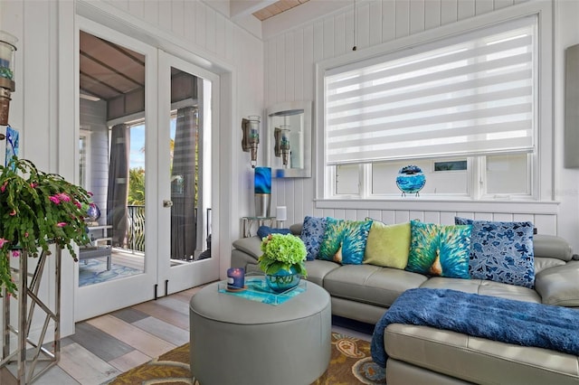 living room featuring french doors, light hardwood / wood-style floors, and wooden walls