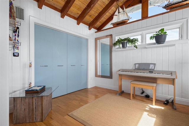 miscellaneous room with wood walls, lofted ceiling with beams, light hardwood / wood-style floors, and wooden ceiling